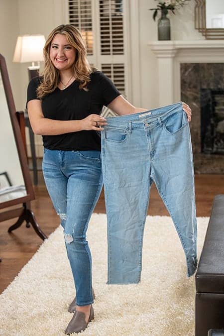 Woman holding up her old jeans